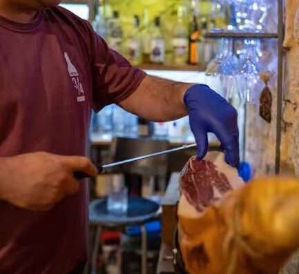 a bar owner cut some italian dry ham for a Wine tasting at San Donato Val di Comino